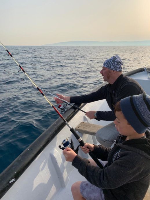 A man and a boy are fishing in a private boat in the Mediterranean Sea 